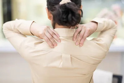 Woman massaging shoulders due to back pain